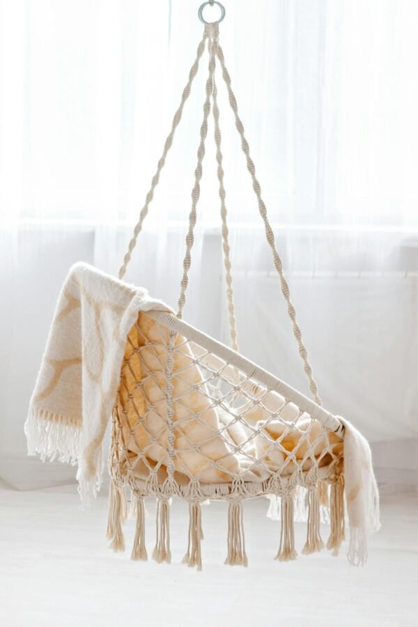 A stylish hanging chair draped with a blanket in a bright, airy room.